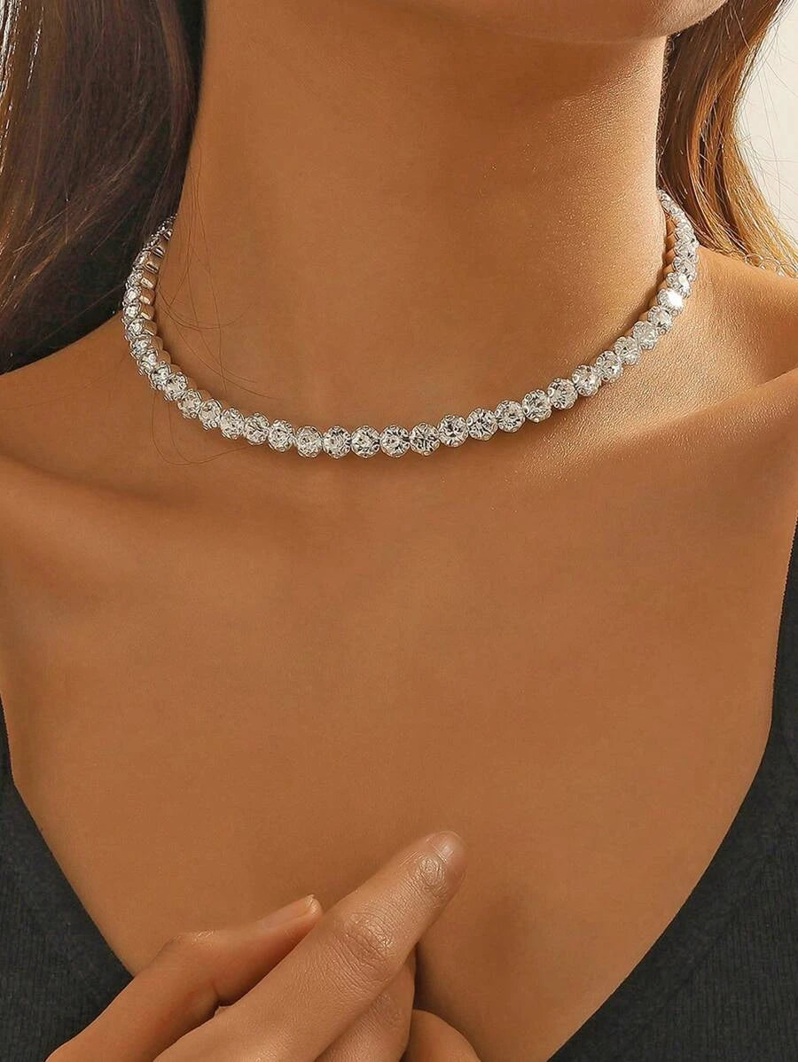 A close-up image of a woman wearing a silver choker necklace encrusted with cubic zirconia crystals.