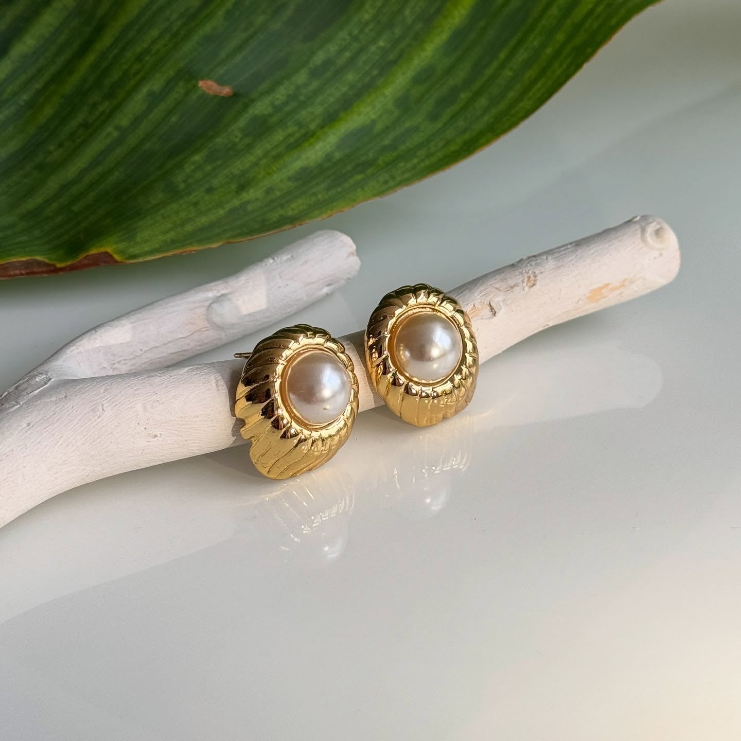 Gold shell-shaped stud earrings with a central pearl, combining elegance and timeless charm for women.