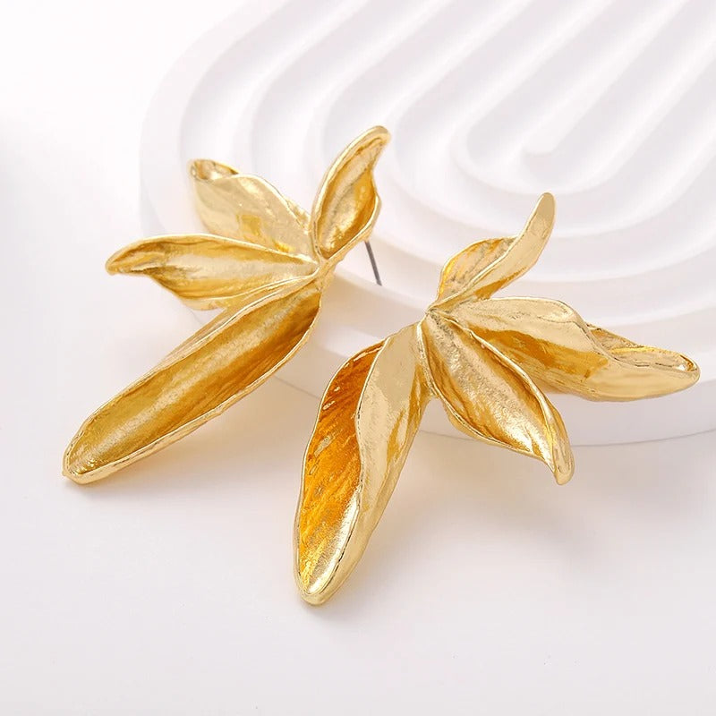 Gold leaf-shaped earrings on a white background