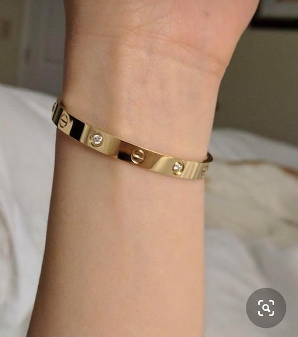 Gold bracelet with diamond accents on a wrist against a neutral background
