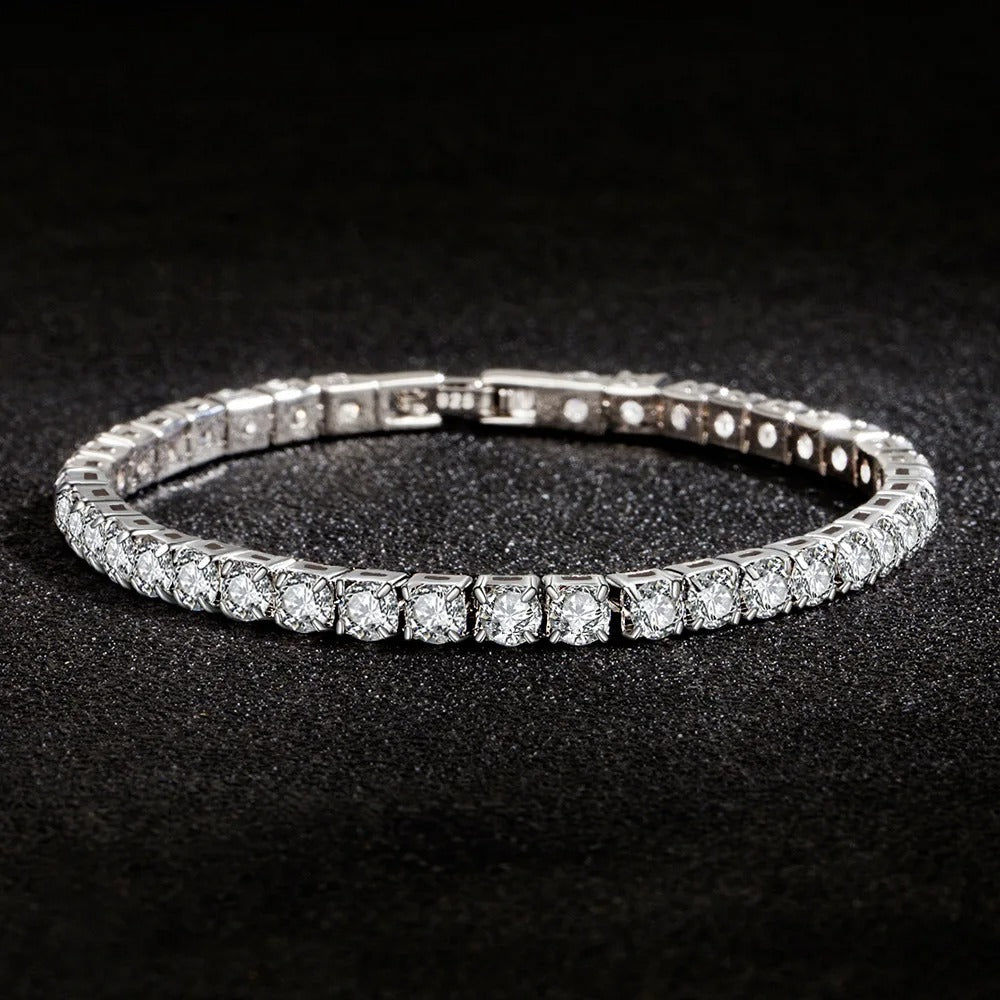 Stylish silver tennis bracelet with sparkling round-cut stones placed on a black textured surface.