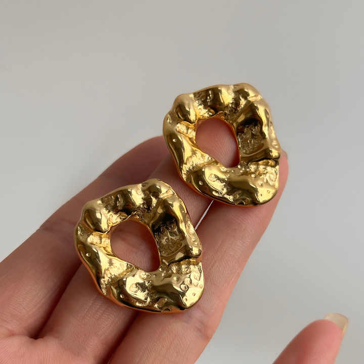 Trendy hammered gold earrings with organic cut-out shape, bold and stylish statement studs for everyday chic fashion.