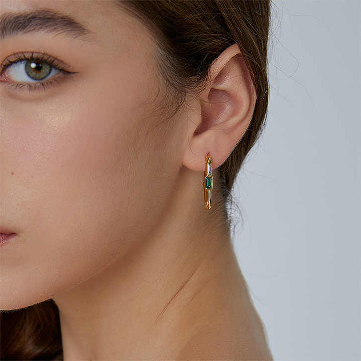 Gold plated hoop earrings with green stone worn by woman, stylish minimalist jewellery perfect for office wear and parties