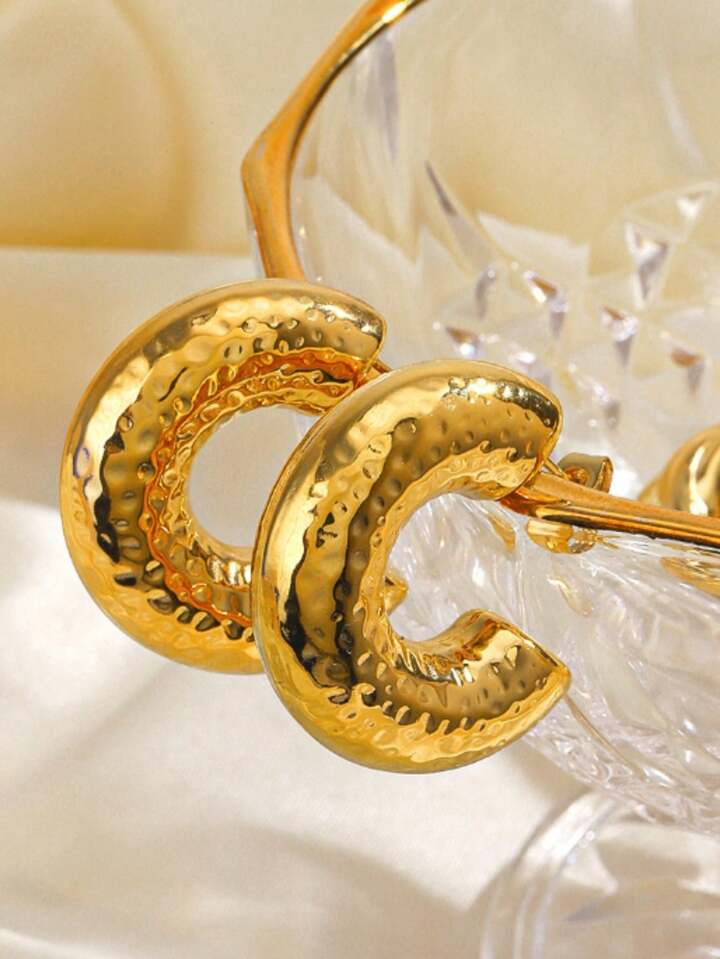 Gold hoop earrings on a soft white background