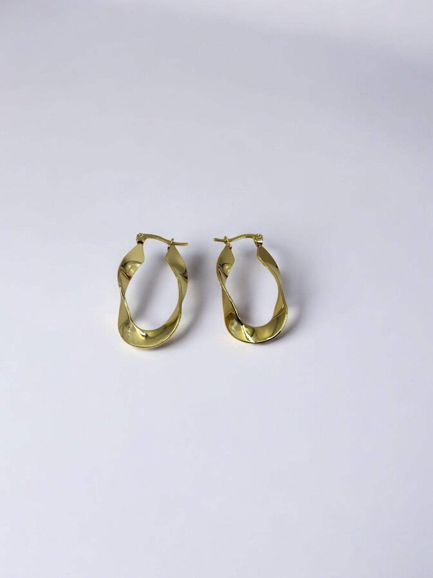 Elegant twisted gold hoop earrings on plain white background, stylish lightweight design for daily wear and special occasions.