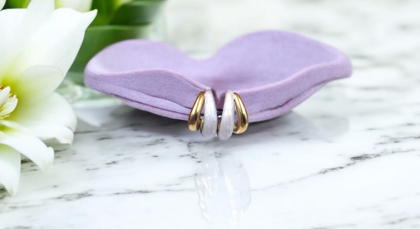 Elegant gold and white enamel hoop earrings placed on lavender holder, perfect lightweight jewelry for stylish women.