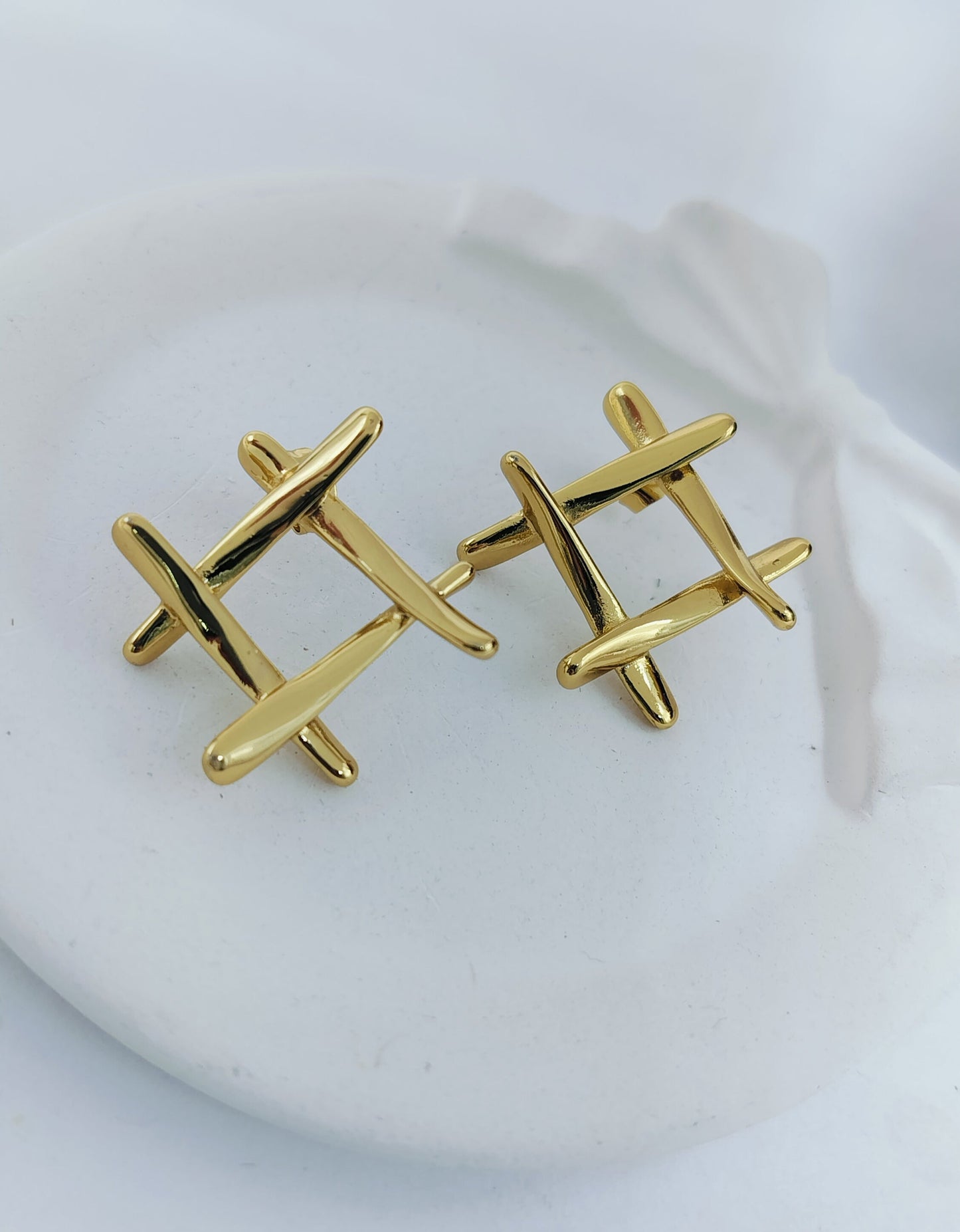 A pair of gold-plated stainless steel hashtag stud earrings displayed on a white surface.