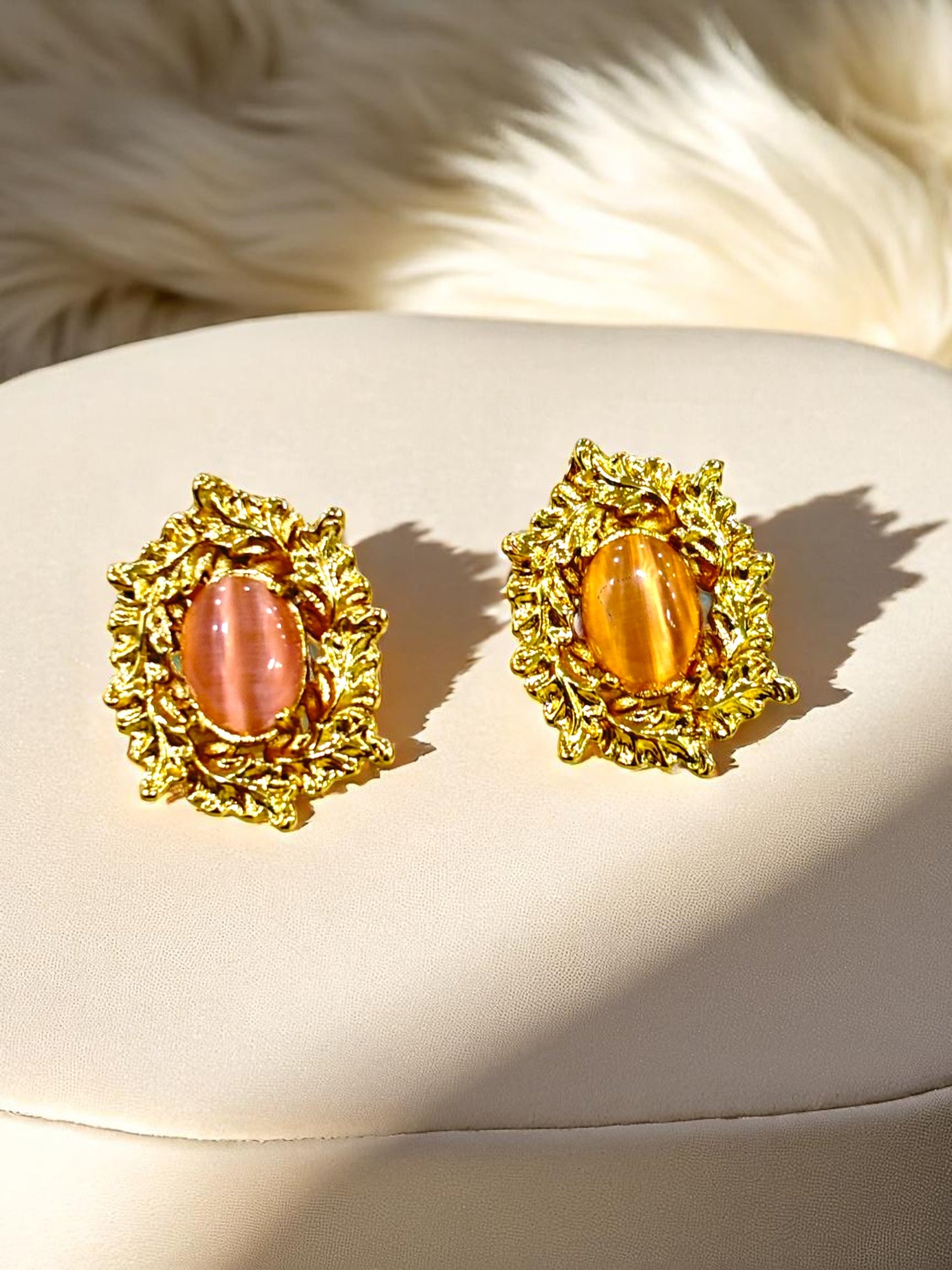 Gold plated vintage-style stud earrings with oval pink and amber gemstones on soft beige background – Glampouch jewelry