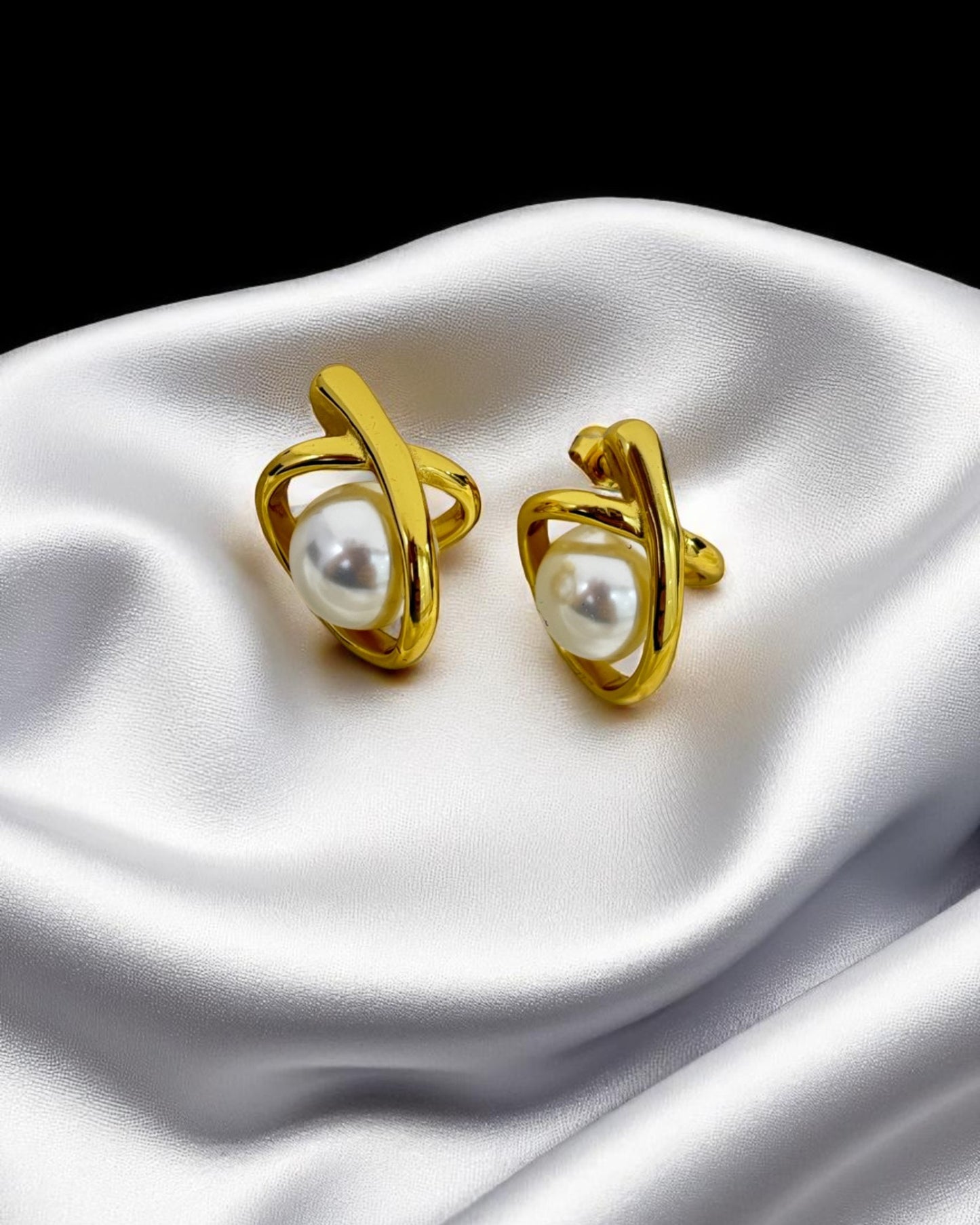 Elegant gold-plated stud earrings with pearl center, showcased on luxurious white satin – Glampouch jewelry