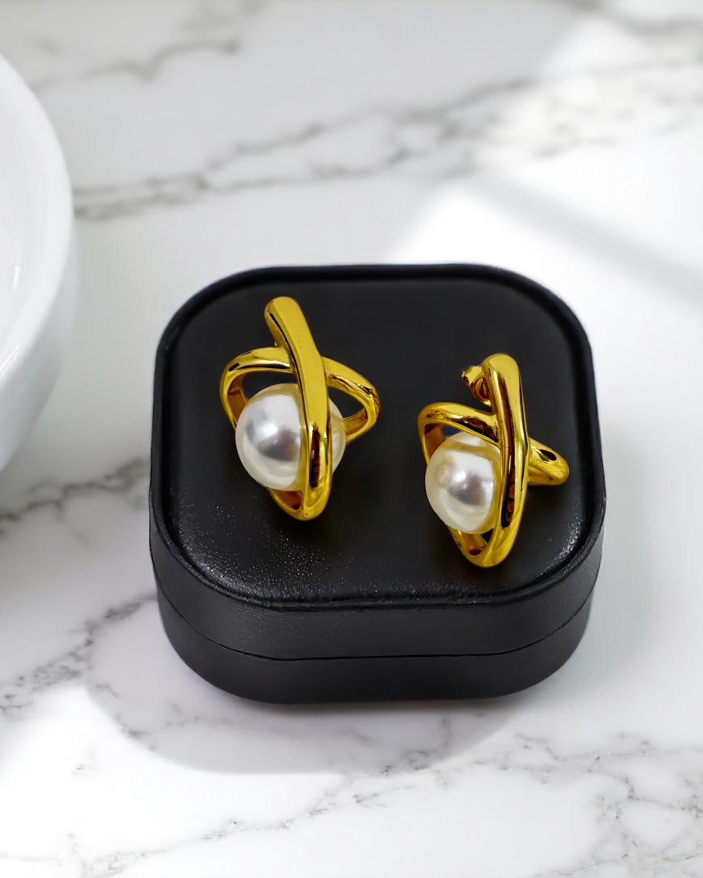 Stylish gold-plated pearl stud earrings displayed in a sleek black jewelry box – Glampouch exclusive design