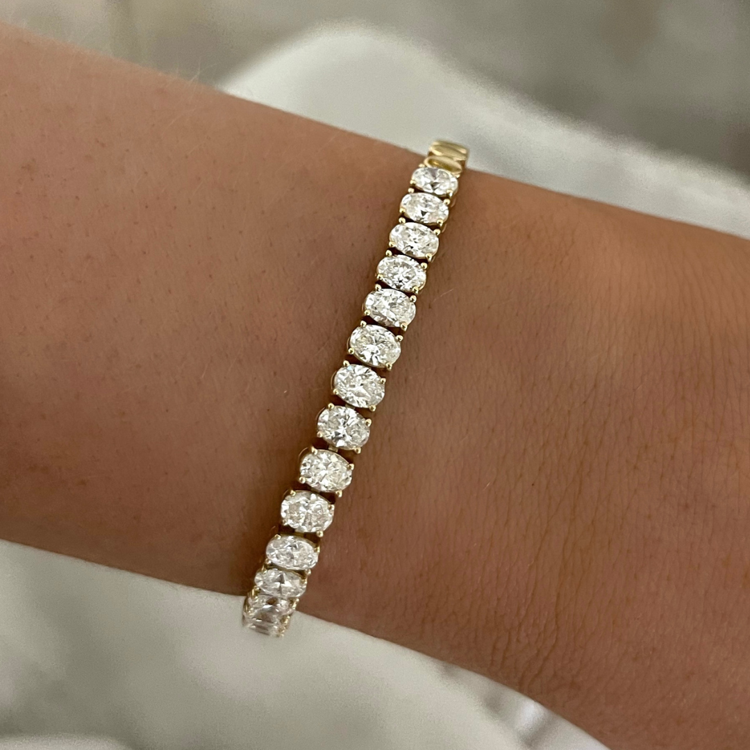 Gold tennis bracelet with sparkling round stones worn on the wrist.