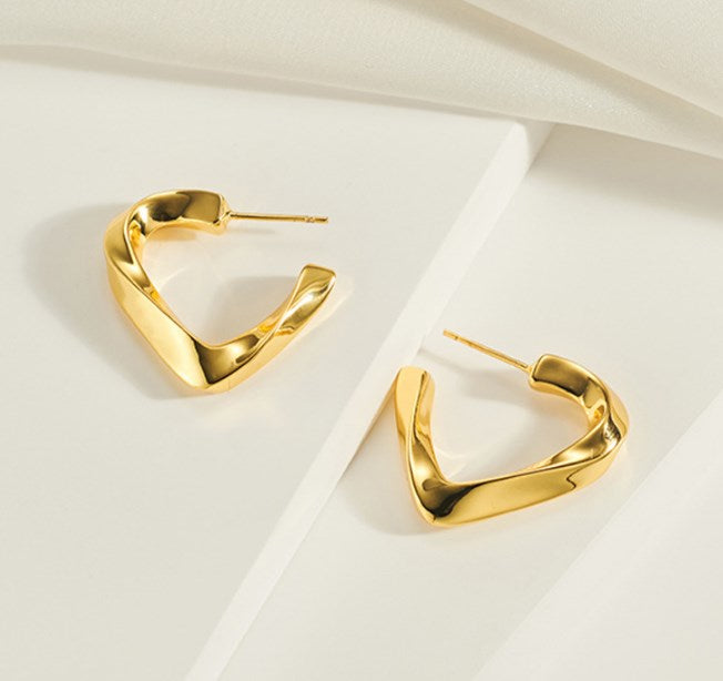 Elegant gold heart-shaped earrings on white surface, stylish lightweight jewelry perfect for women’s daily and party wear.