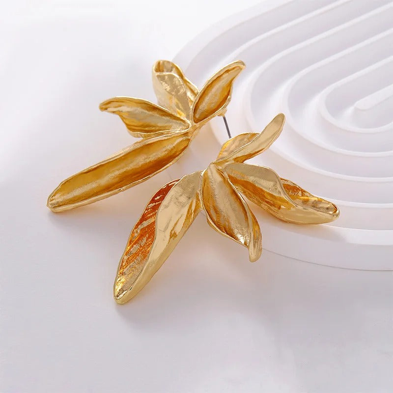 Gold leaf-shaped earrings on a white background