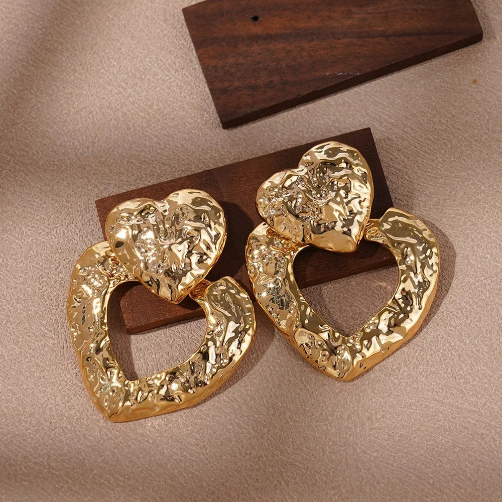 Gold heart-shaped earrings on a brown surface