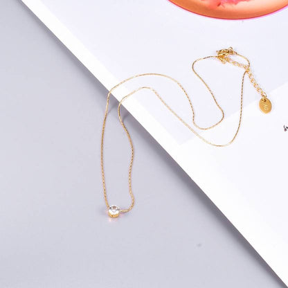Delicate gold chain necklace with solitaire diamond pendant placed on magazine background.