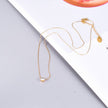 Delicate gold chain necklace with solitaire diamond pendant placed on magazine background.