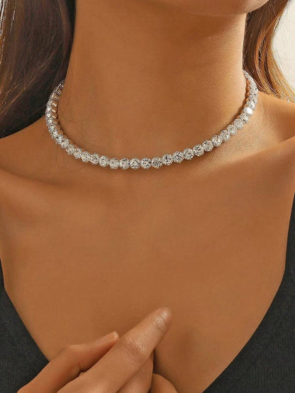 A close-up image of a woman wearing a silver choker necklace encrusted with cubic zirconia crystals.