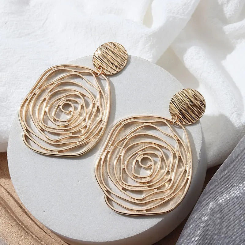 Gold spiral earrings on a white marble surface