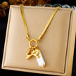Gold necklace with a bow and pearl charm on a beige box