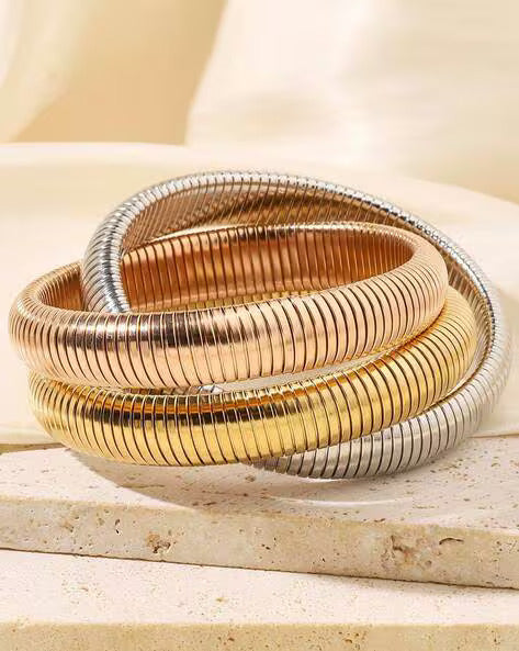 A set of three interlocking snake coil bangle bracelets in gold, rose gold, and silver colors.