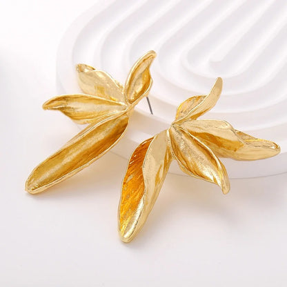 Gold leaf-shaped earrings on a white background