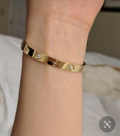 Gold bracelet with diamond accents on a wrist against a neutral background