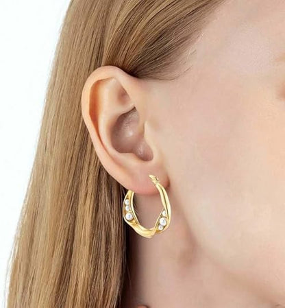 Gold hoop earrings with pearl detailing worn on ear, offering timeless elegance and refined sophistication for daily style.