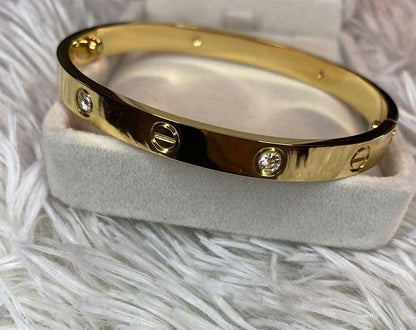 Gold bracelet with diamonds on a white stand against a white fur background