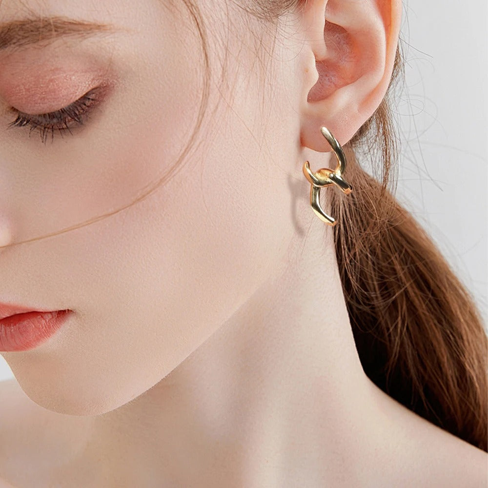 Elegant gold plated twisted hoop earrings styled on model, adding a bold yet refined touch to modern fashion looks.
