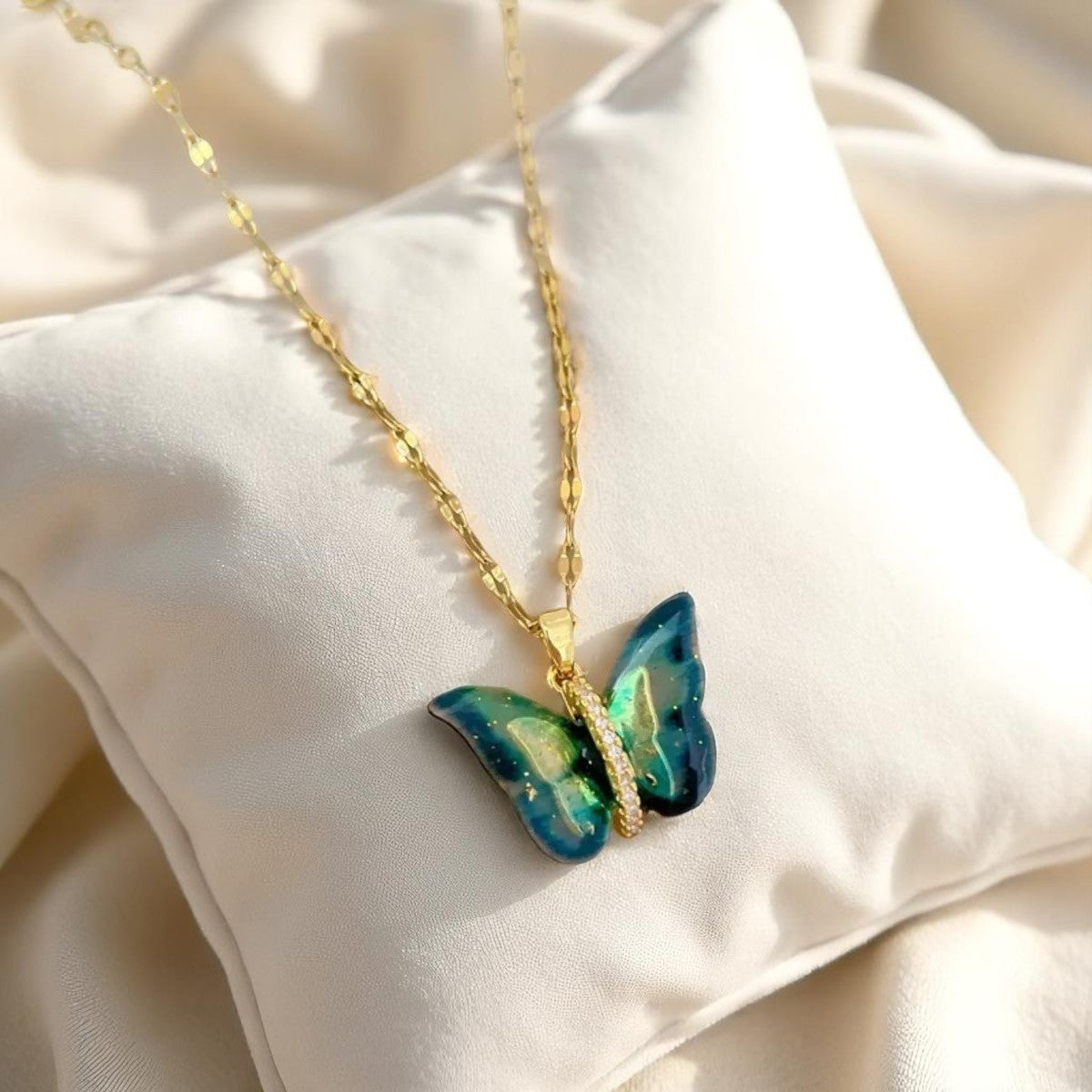 Gold necklace with a butterfly pendant on a beige fabric background