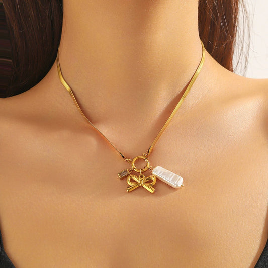 Gold necklace with a bow and pearl pendant on a model