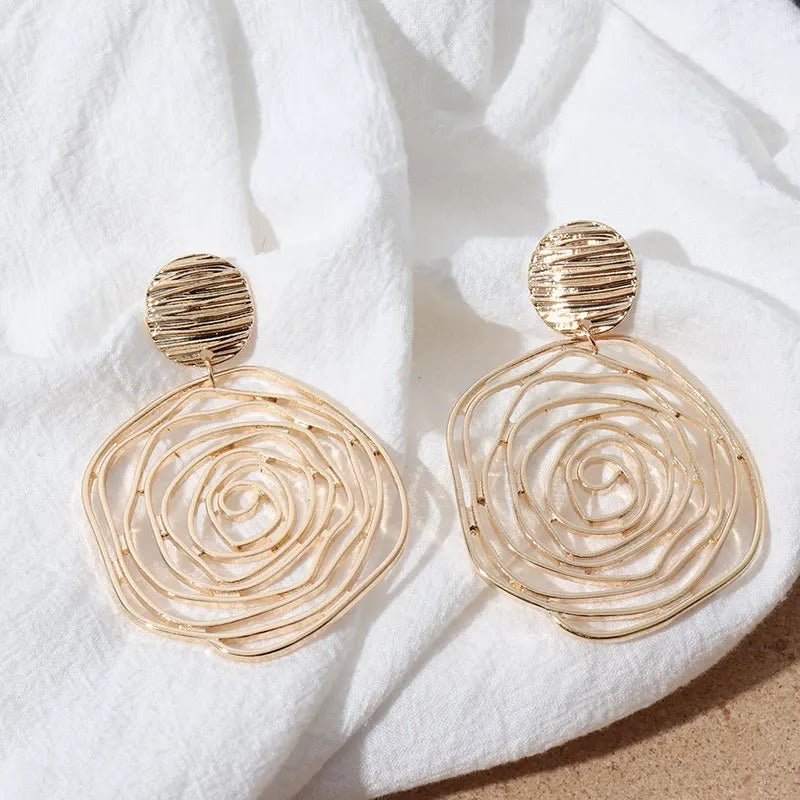 Gold wire earrings on a white fabric background