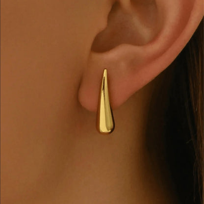 Close-up shot of a stylish gold-plated drop earring worn on a person's earlobe.