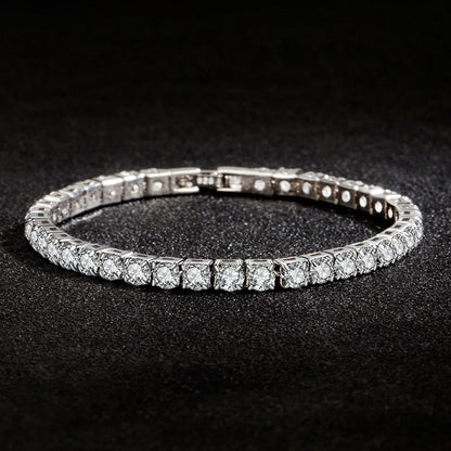 Stylish silver tennis bracelet with sparkling round-cut stones placed on a black textured surface.
