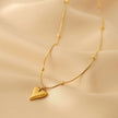 Elegant gold heart pendant necklace with delicate beaded chain on golden satin fabric.