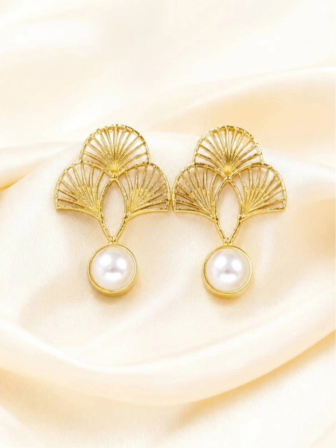 Pair of gold-plated ginkgo fan drop earrings with white faux-pearl drops on cream satin