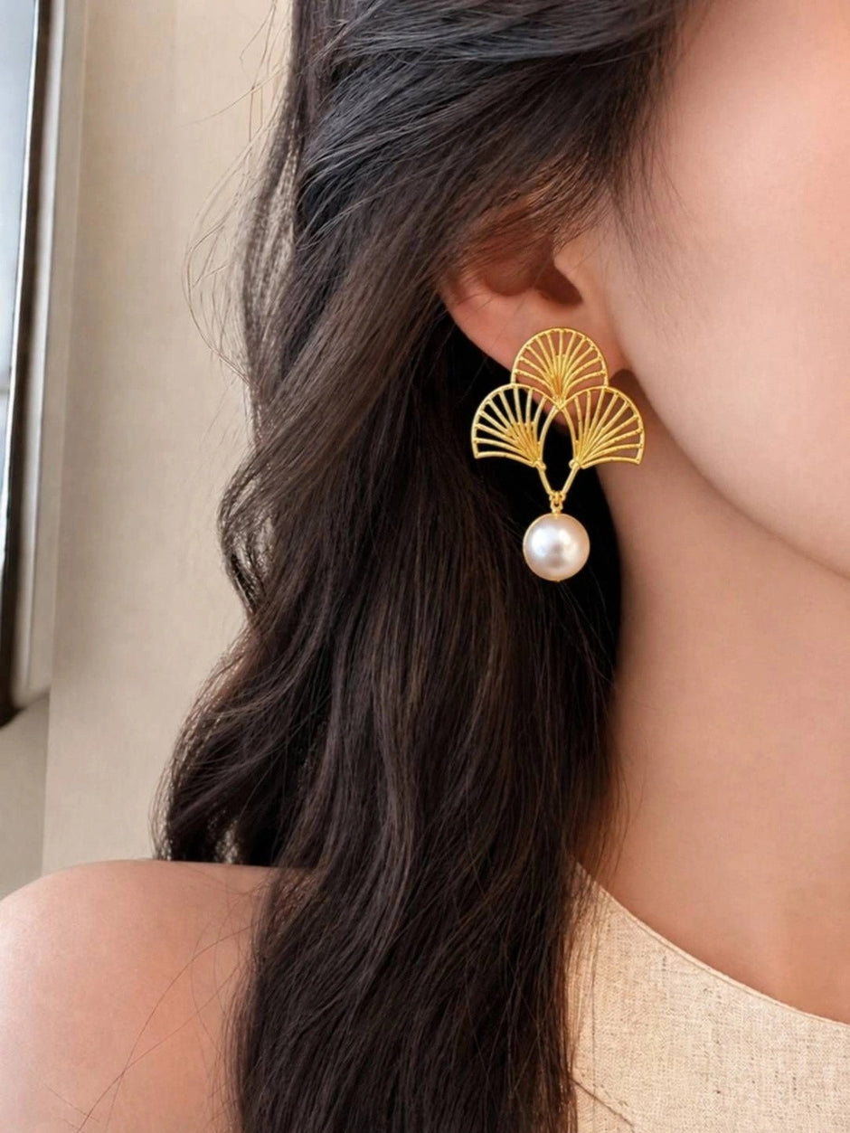 Model wearing a gold ginkgo fan pearl drop earring showing scale and fit on ear