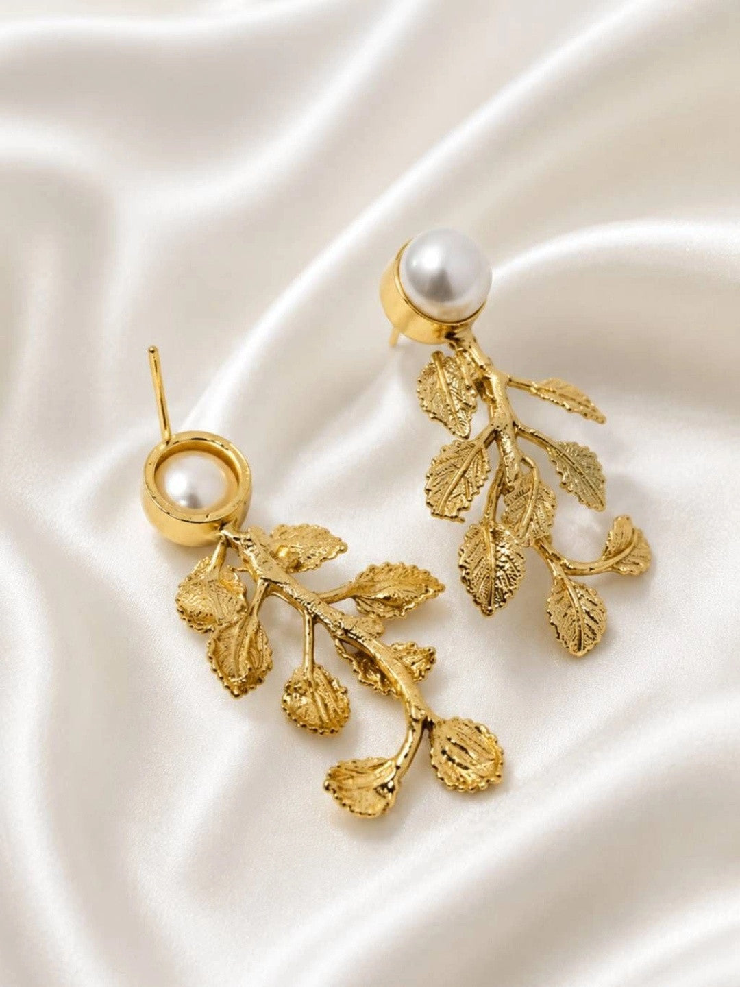 Side view of gold leaf drop earrings showing post-back fitting and textured leaf detail on satin