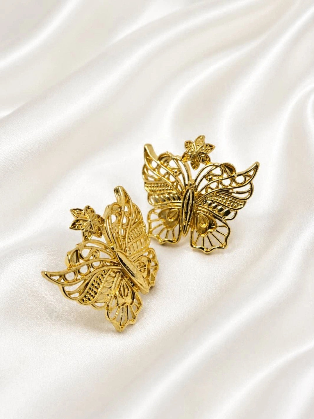 Side-angled close-up of gold butterfly stud earrings showing three-dimensional wing detail