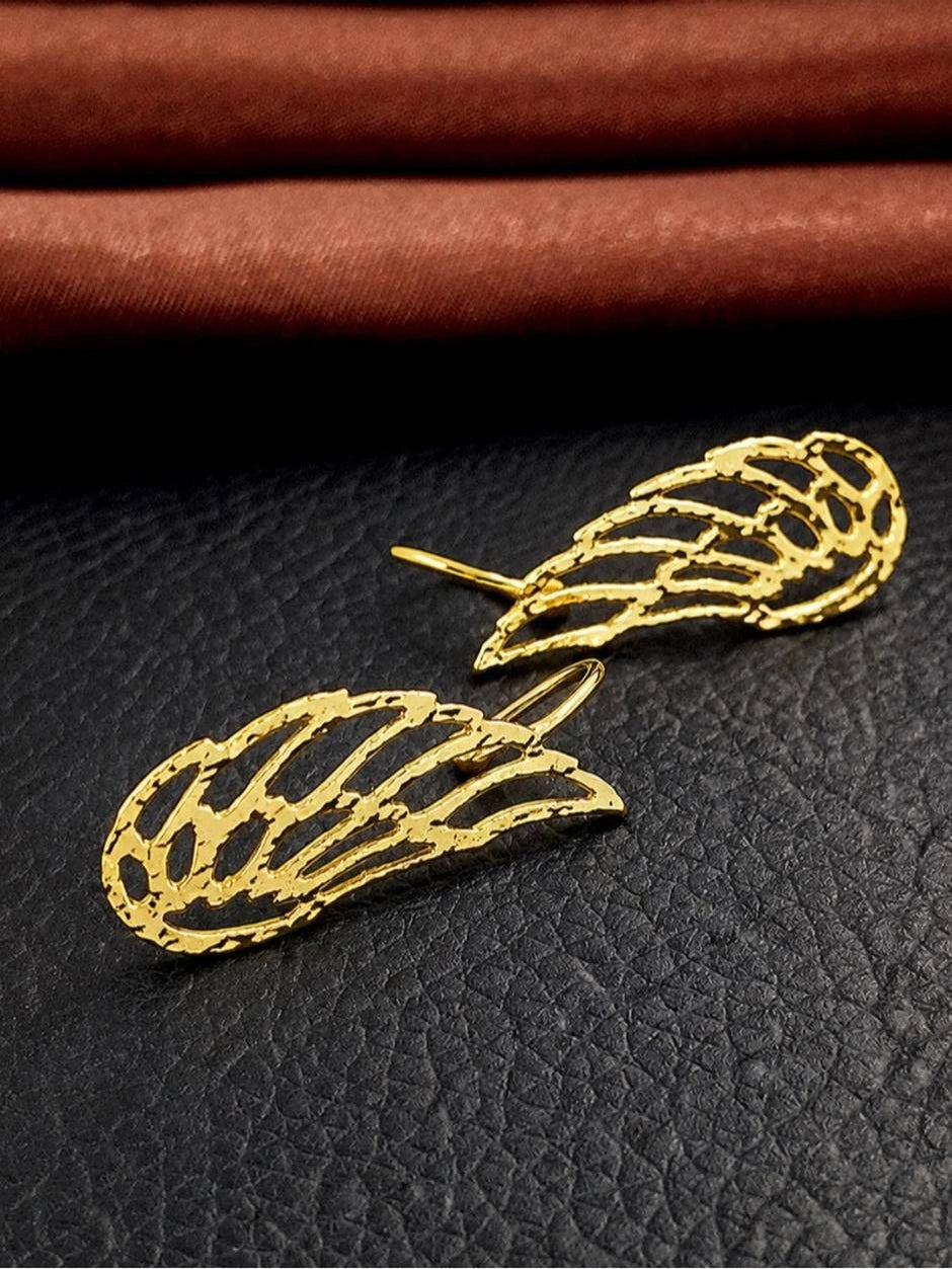 Two gold filigree wing ear cuffs lying flat on black textured leather surface