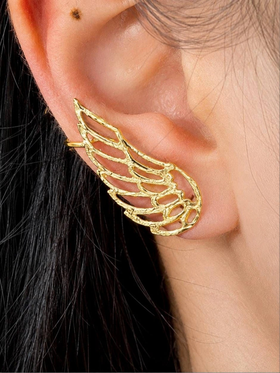 Gold angel wing ear cuff worn on a model's right ear showing full coverage from lobe to upper cartilage