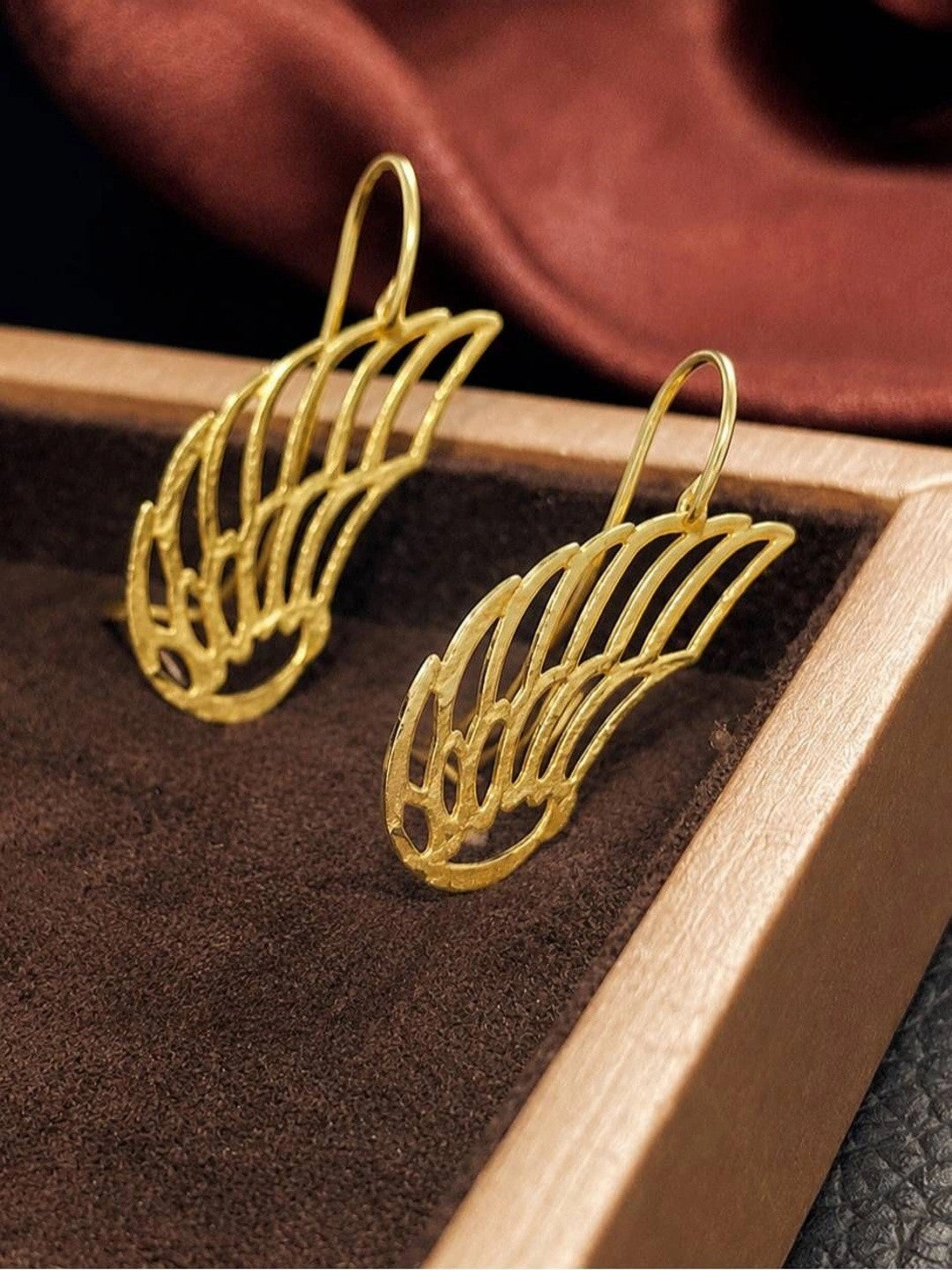 Duplicate of image 05 — same close-up hand shot of gold angel wing ear cuffs
