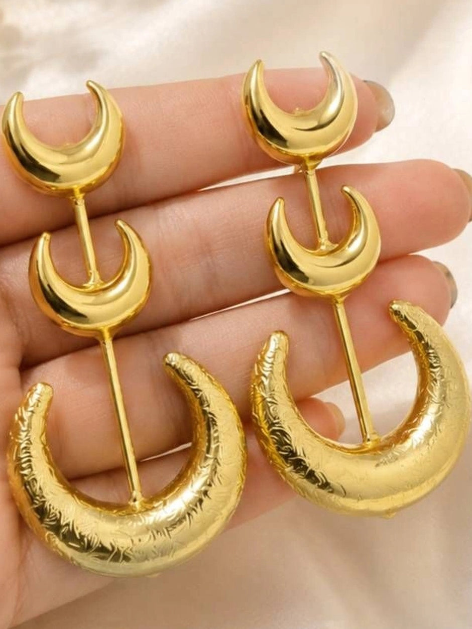 Both gold crescent moon drop earrings resting across a woman's open palm showing scale and detail