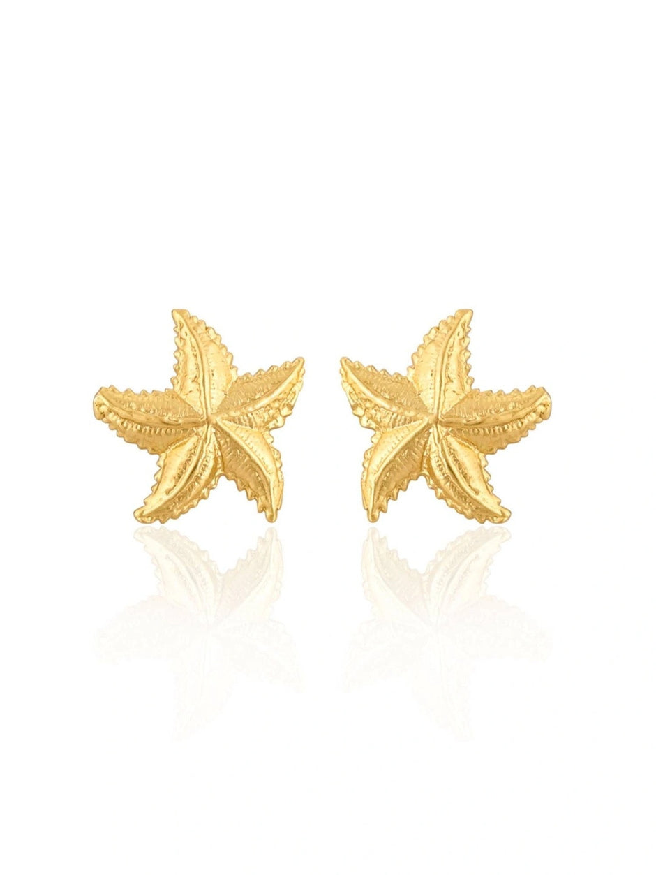 Pair of gold-plated starfish stud earrings isolated on white background with subtle reflection below