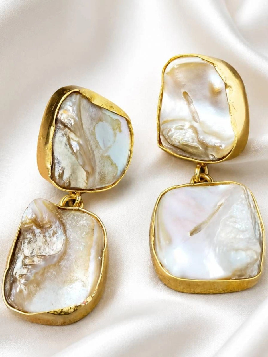 Close-up of gold bezel baroque pearl two-tier drop earrings showing iridescent nacre detail
