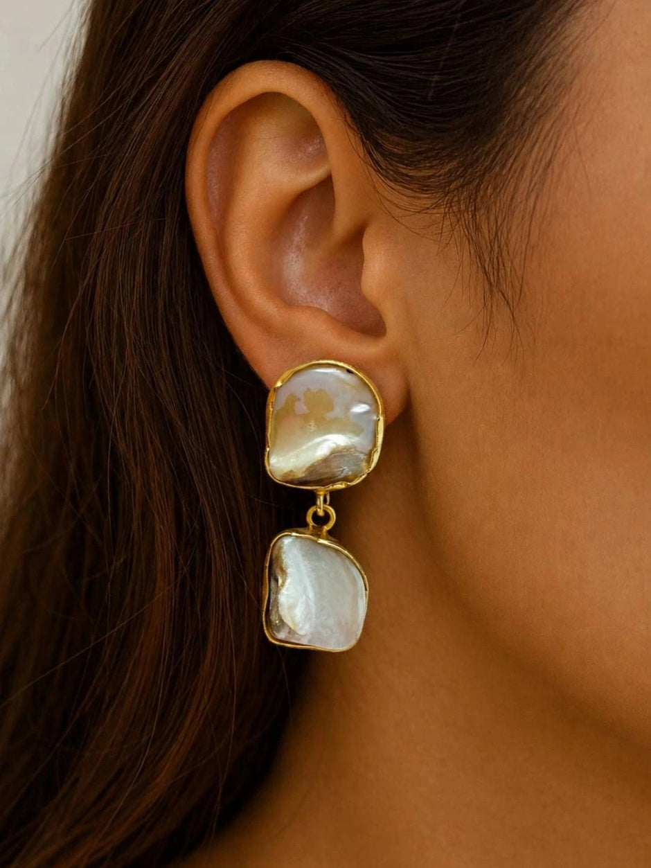 Model wearing gold-plated baroque pearl drop earring on right ear, side profile view