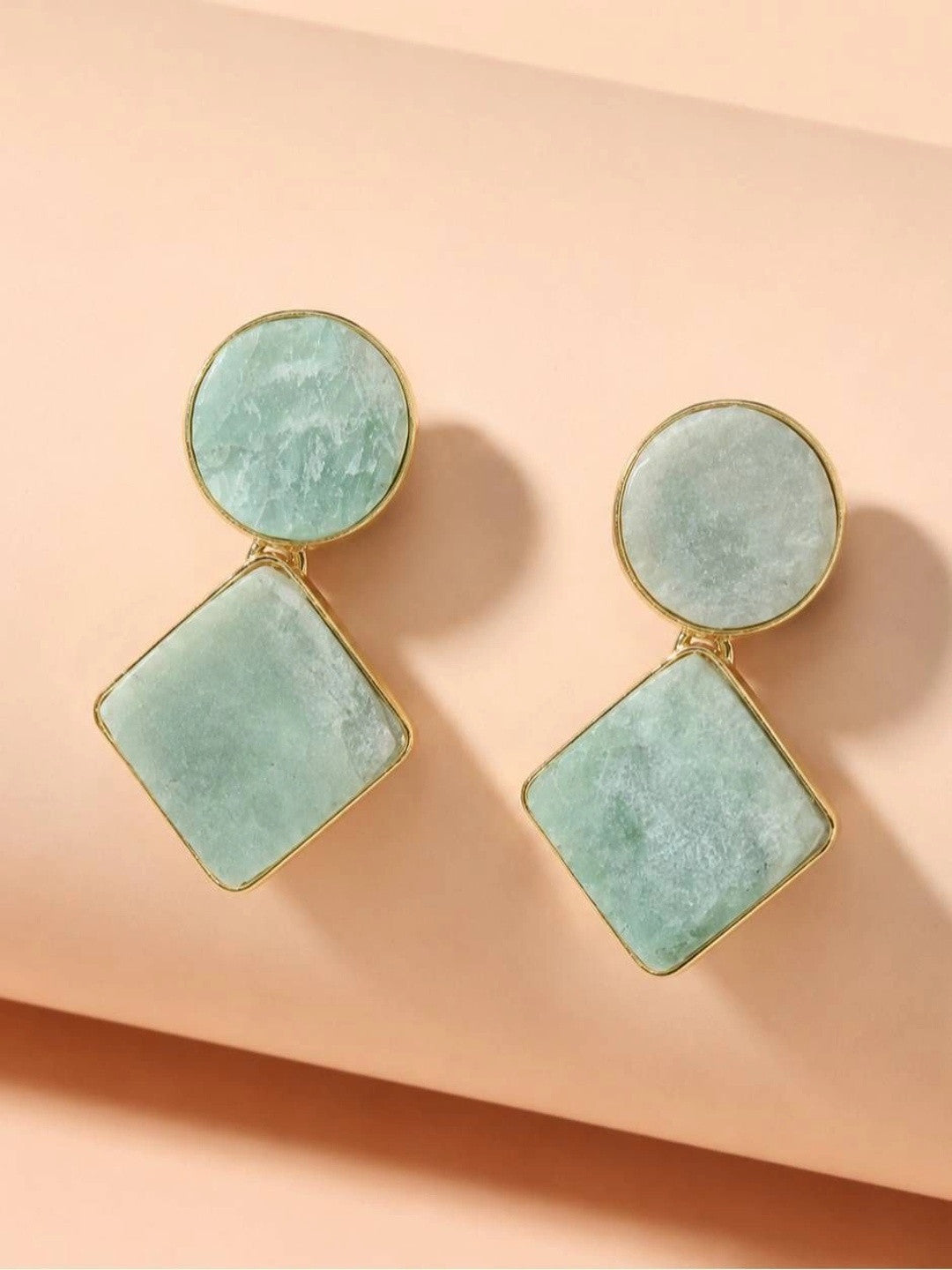 Pair of mint green amazonite geometric drop earrings with gold bezel on a peach surface