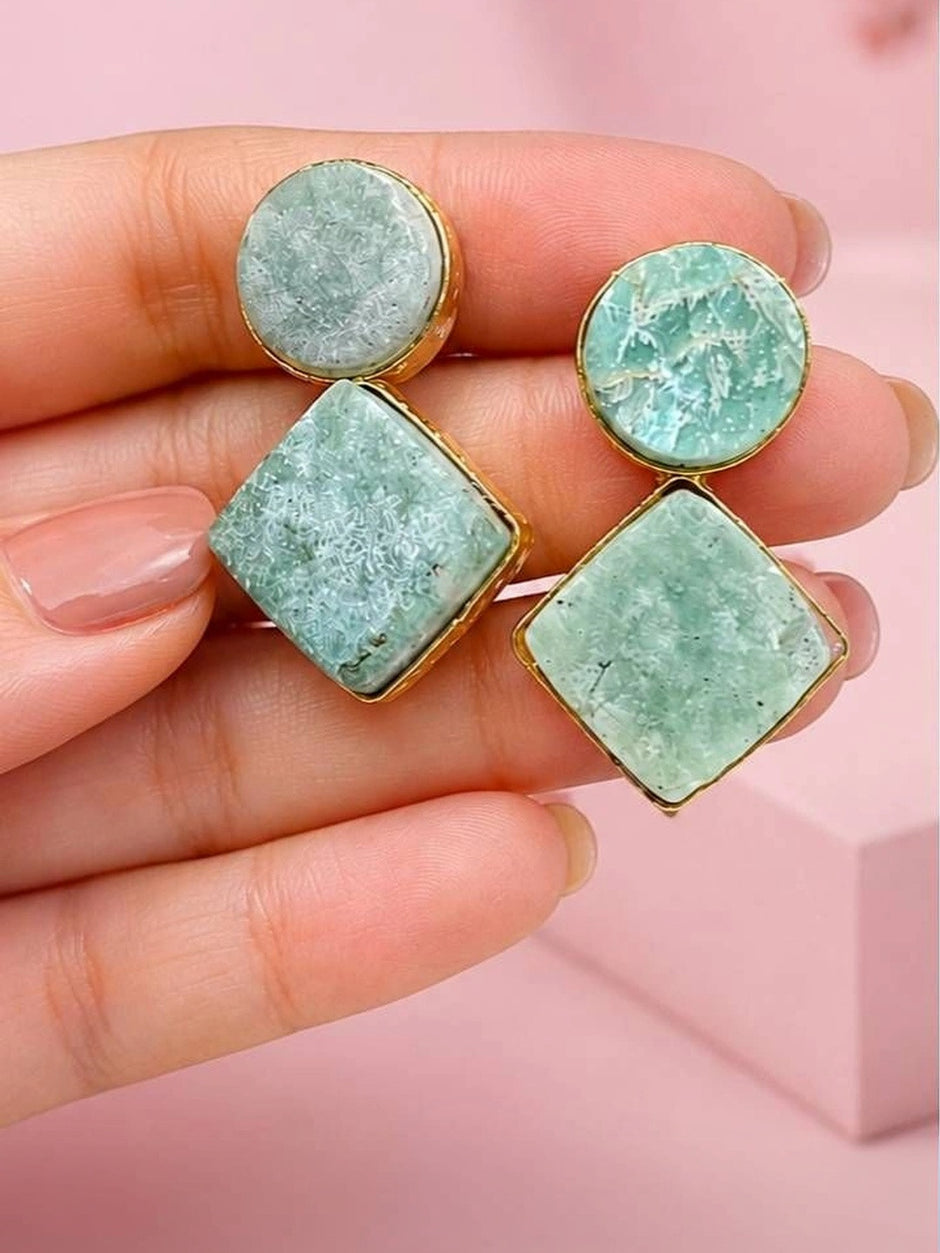 Close-up of two amazonite drop earrings held in hand showing crystal veining detail