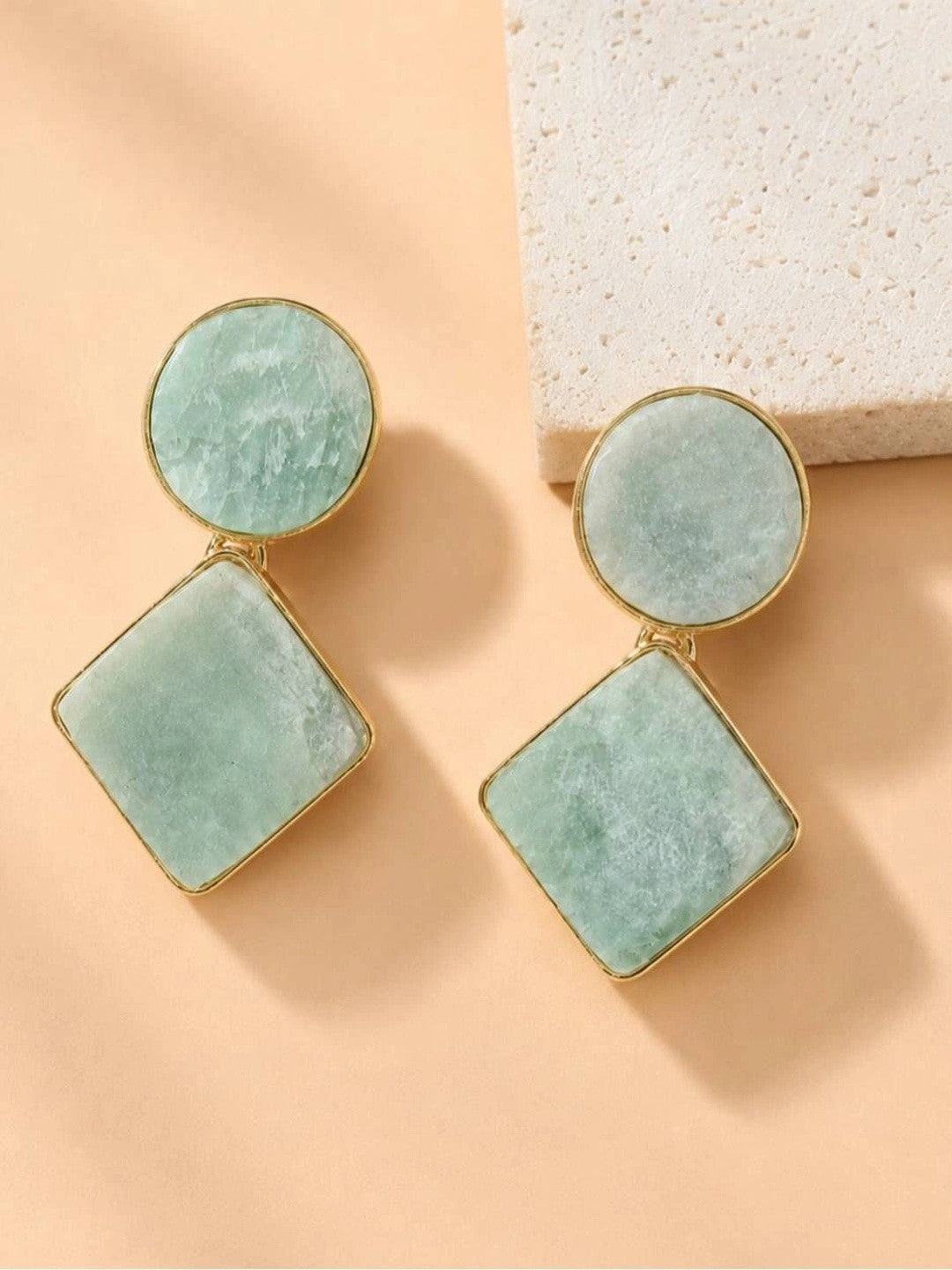 Both amazonite geometric drop earrings laid flat beside a white stone surface