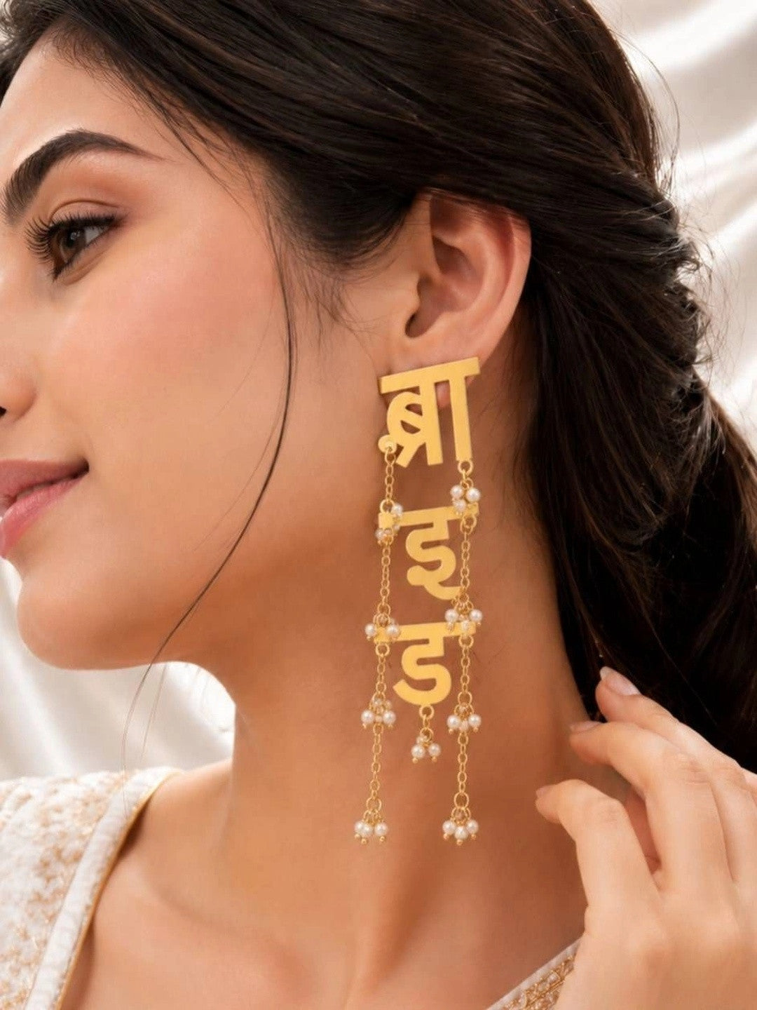 Woman wearing one gold-plated Hindi bride script drop earring showing full length against her ear and neck